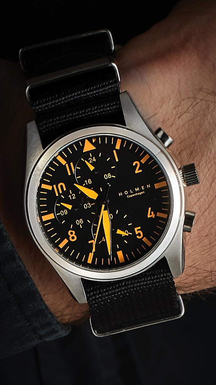 Wristwatch with black strap and orange accents on a wrist