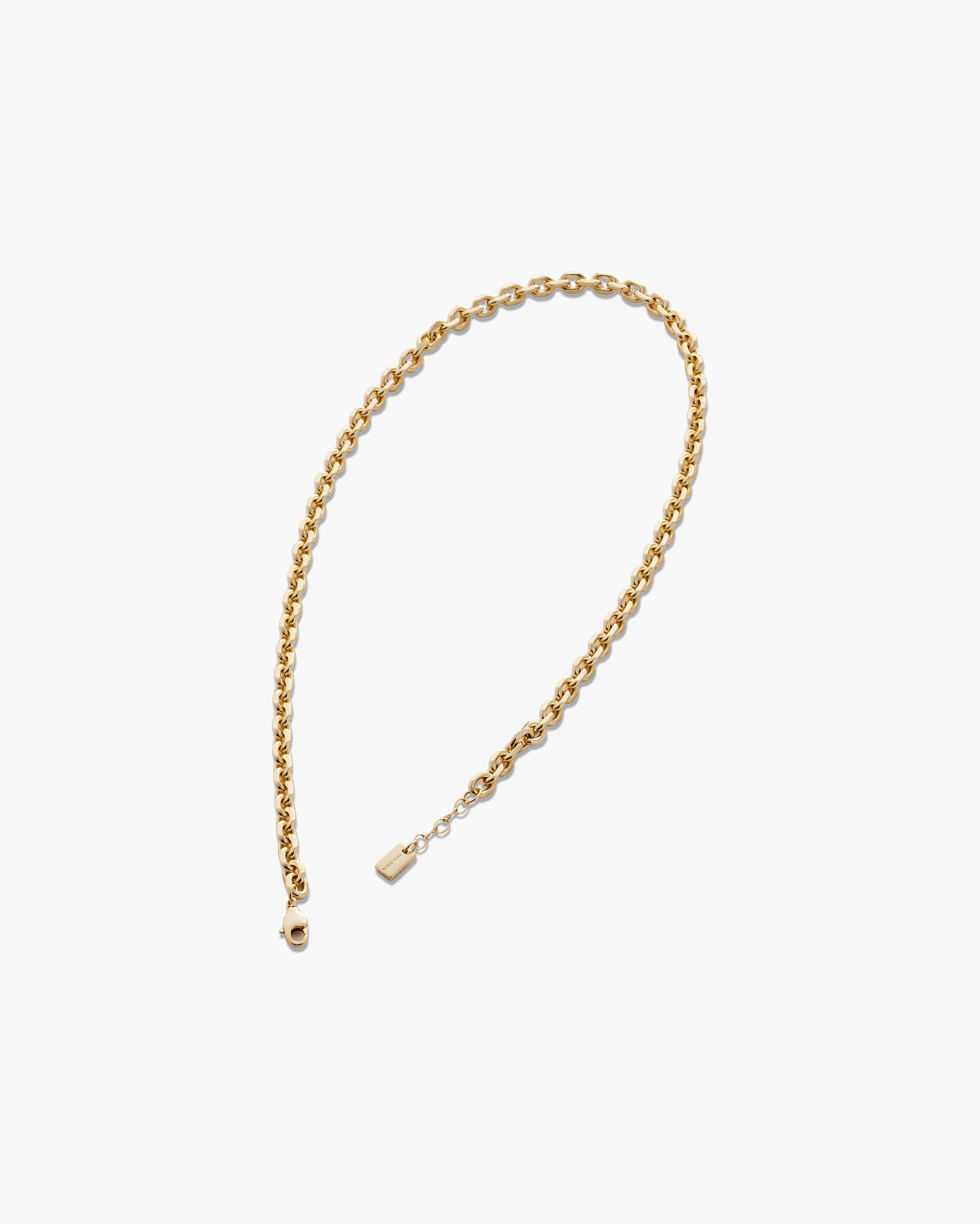 Gold chain necklace on a light grey background