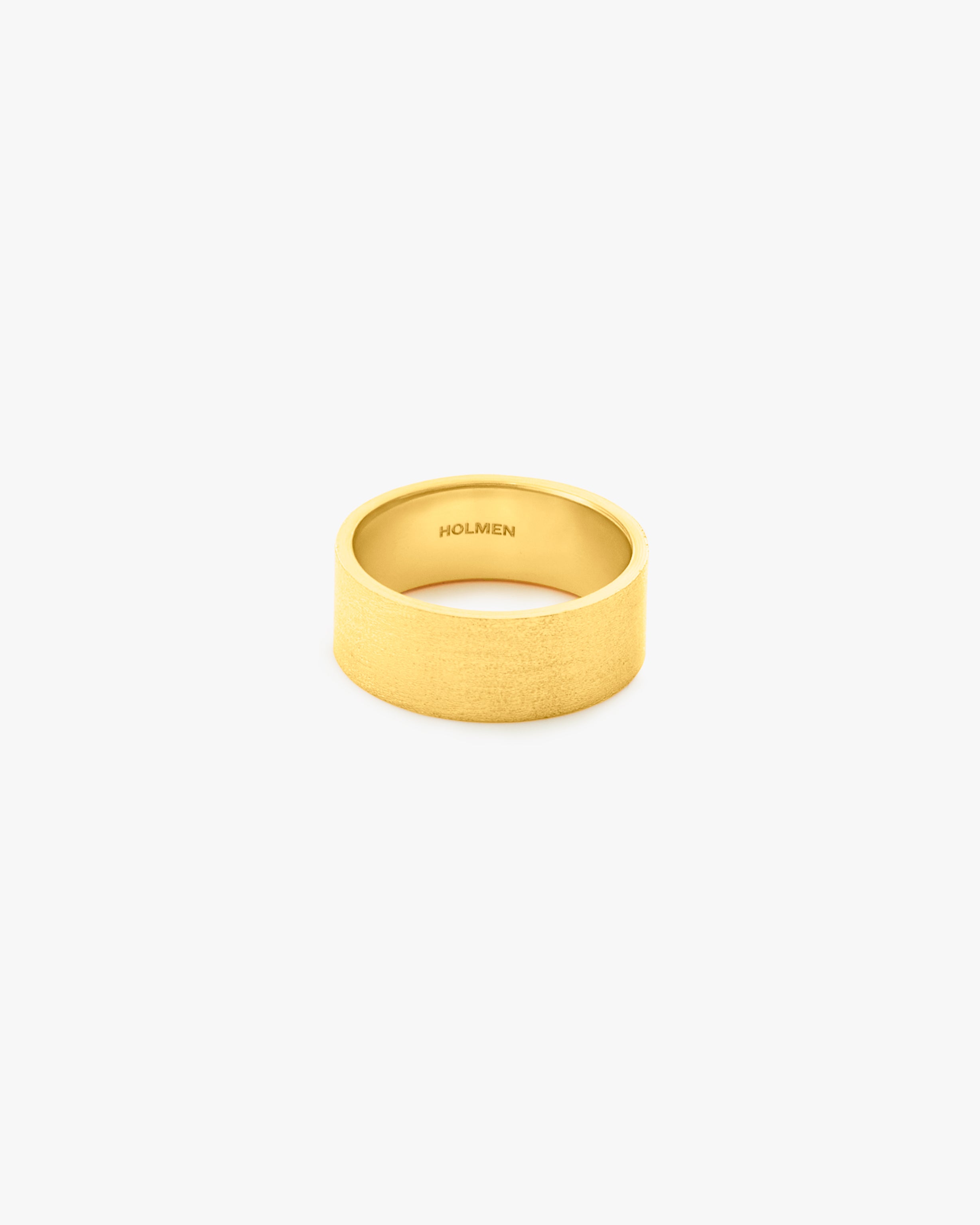 Gold ring with 'HOLMEN' engraving on a light grey background