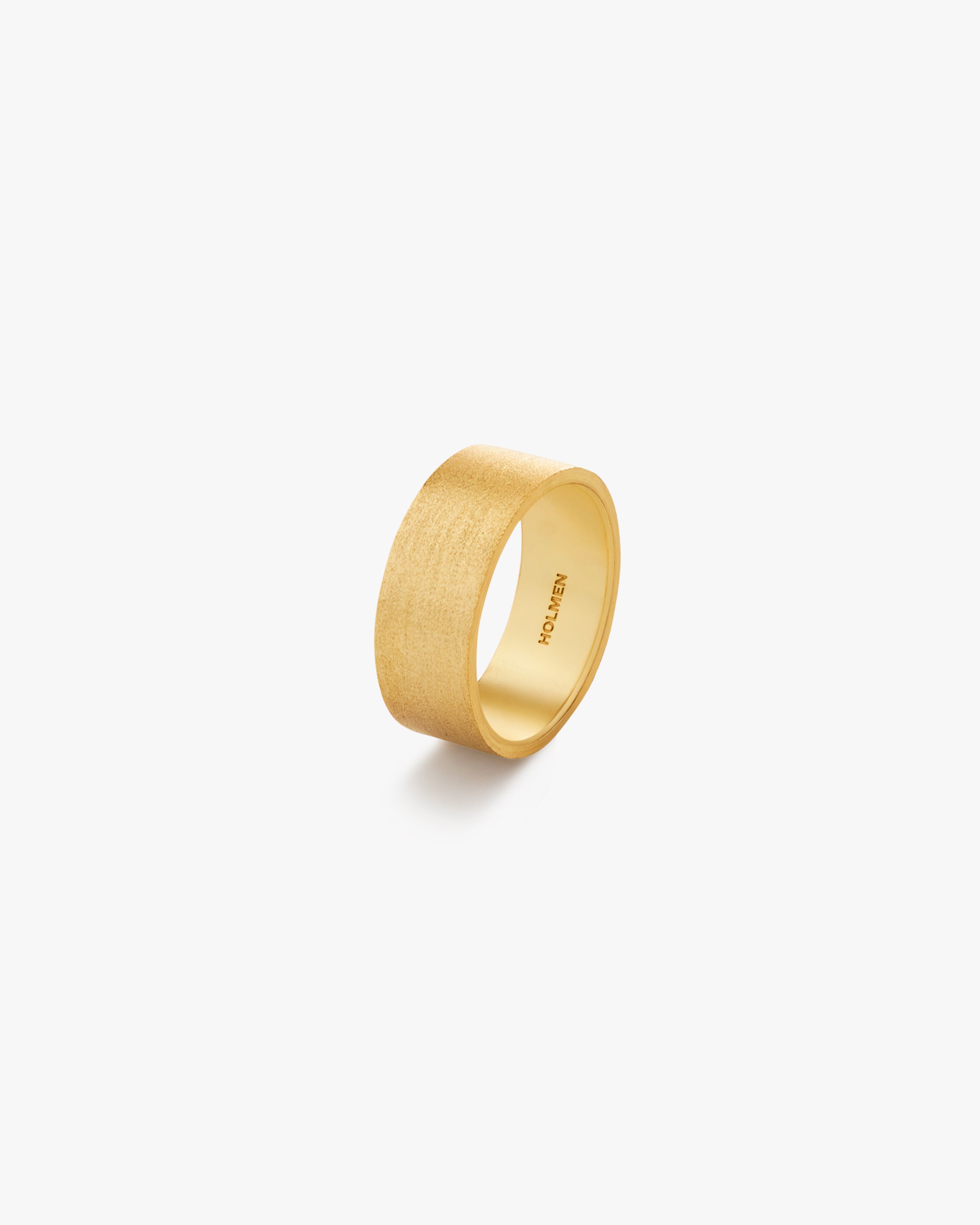 Gold ring with "HOLMEN" branding on a light grey background