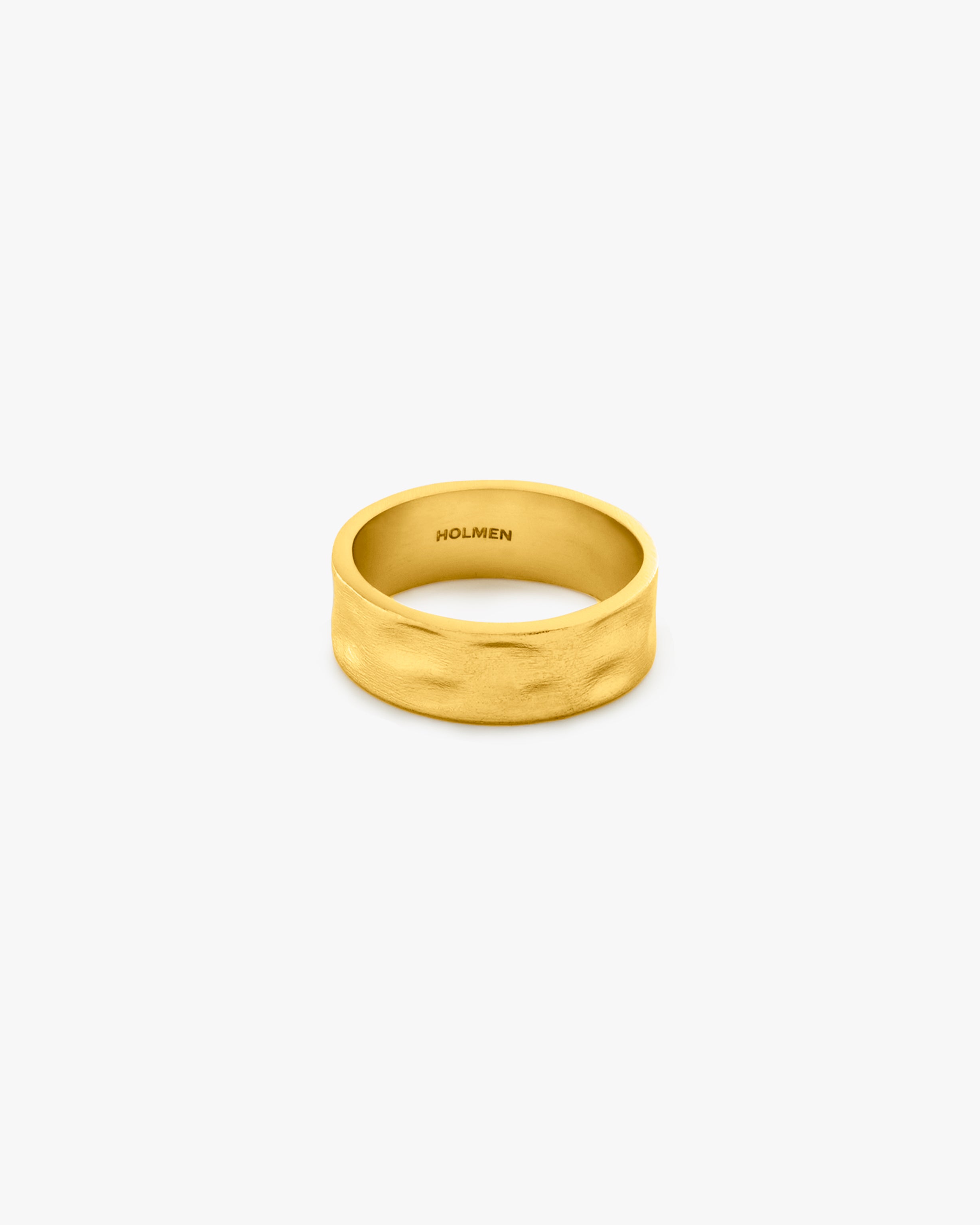 Gold ring with 'HOLMEN' engraving on a light grey background