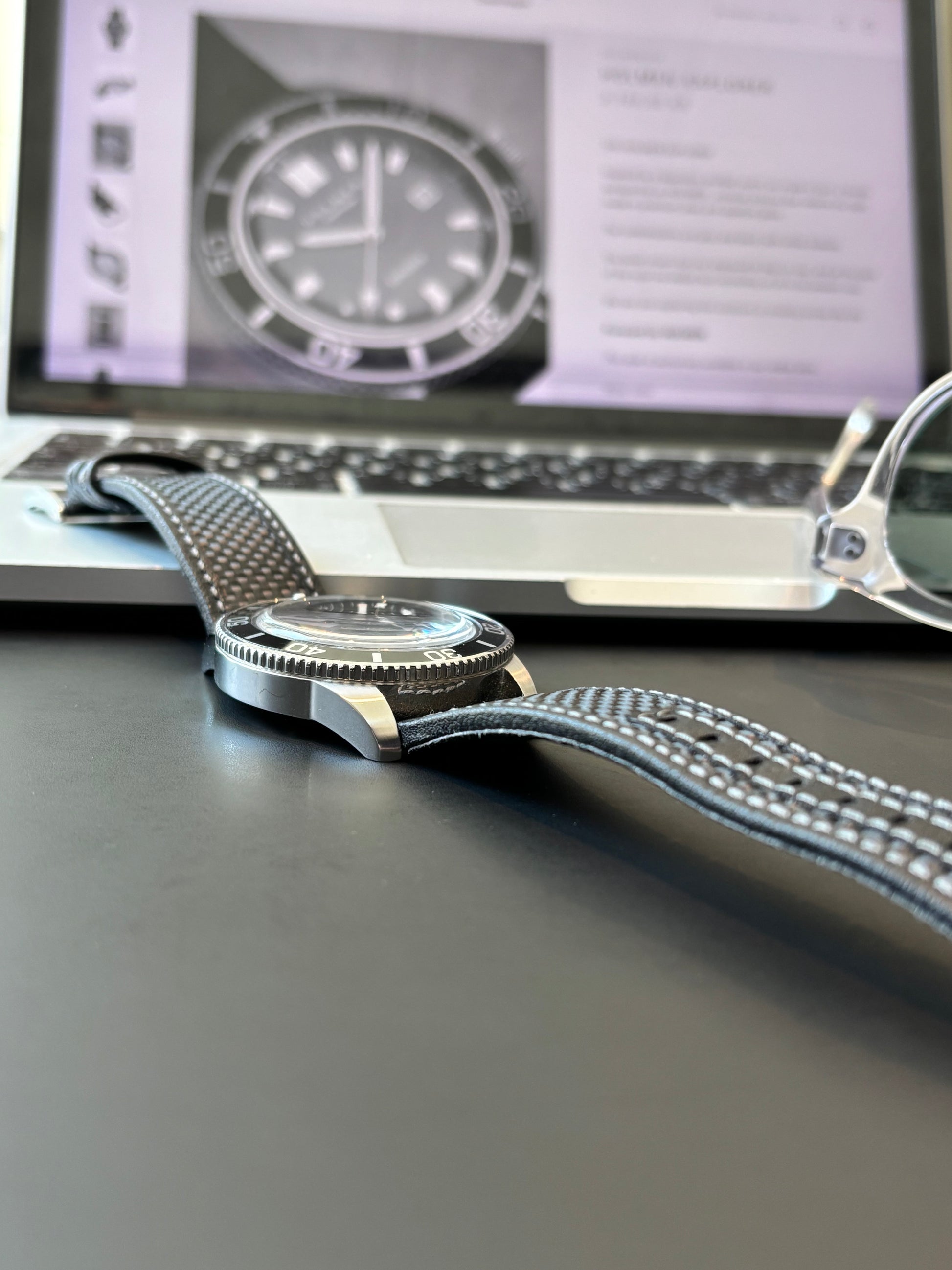 Close-up of a silver watch with a lanyard on a screen displaying a watch image.