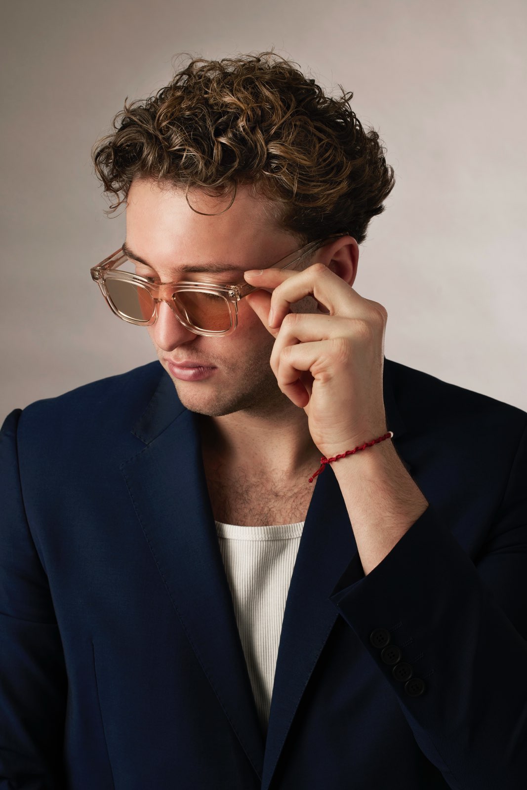 Man adjusting sunglasses with a neutral background