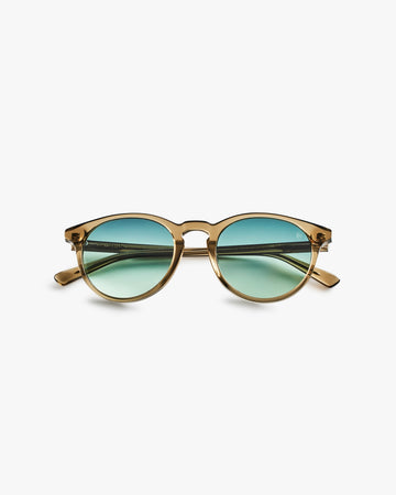 Gold-framed sunglasses with green lenses on a light grey background