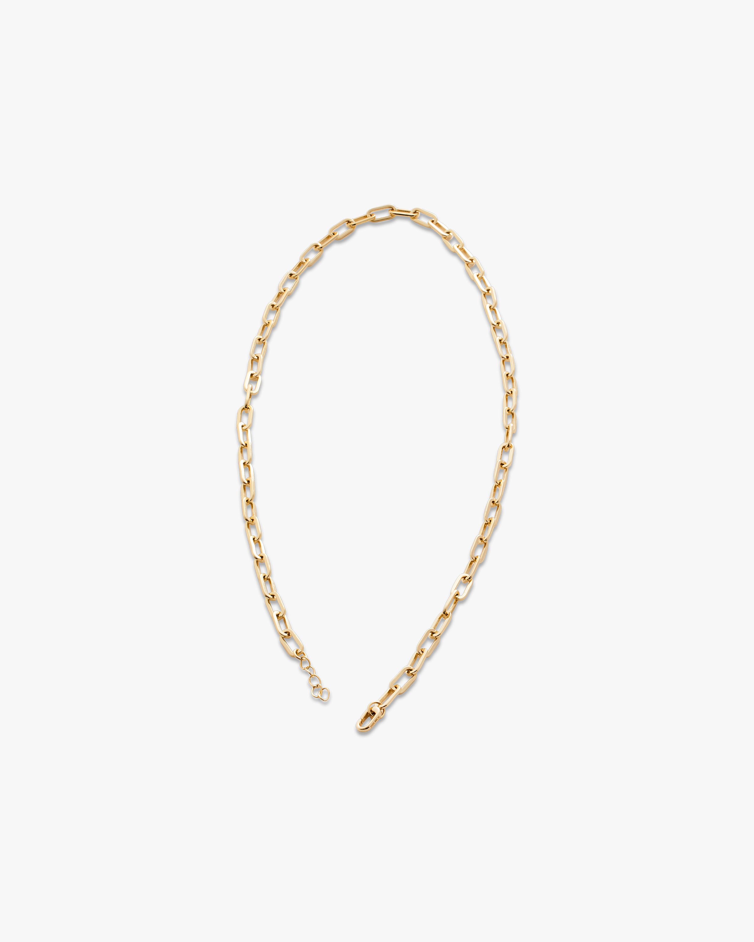 Gold chain necklace on a light grey background