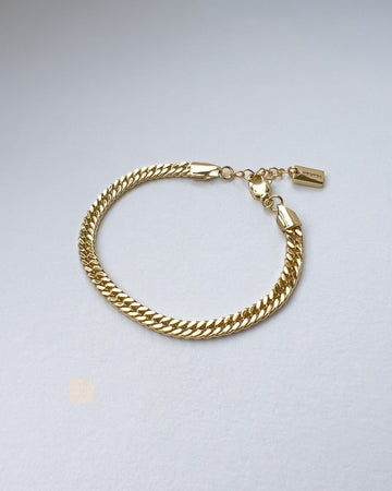 Gold chain bracelet on a light gray background
