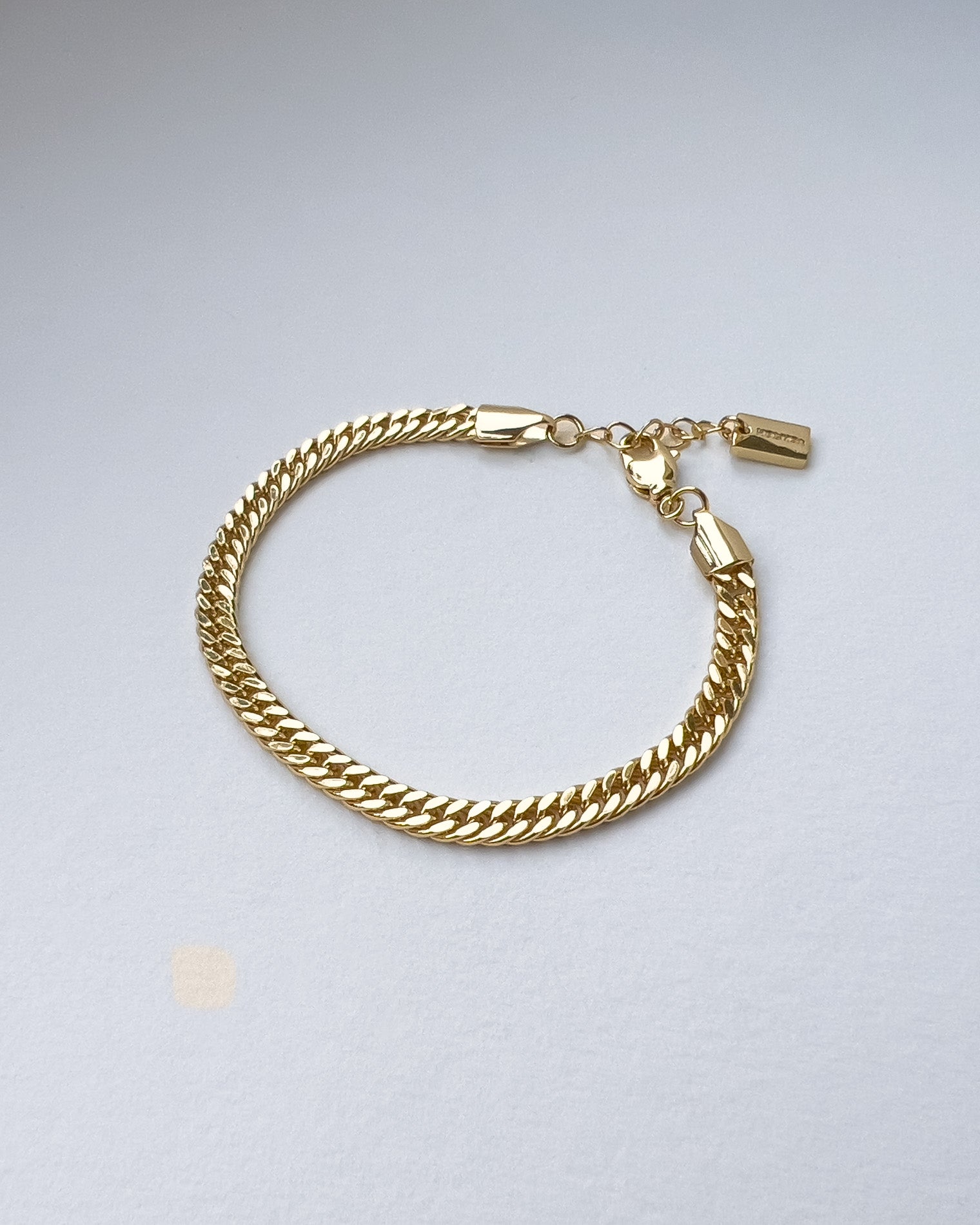 Gold chain bracelet on a light gray background