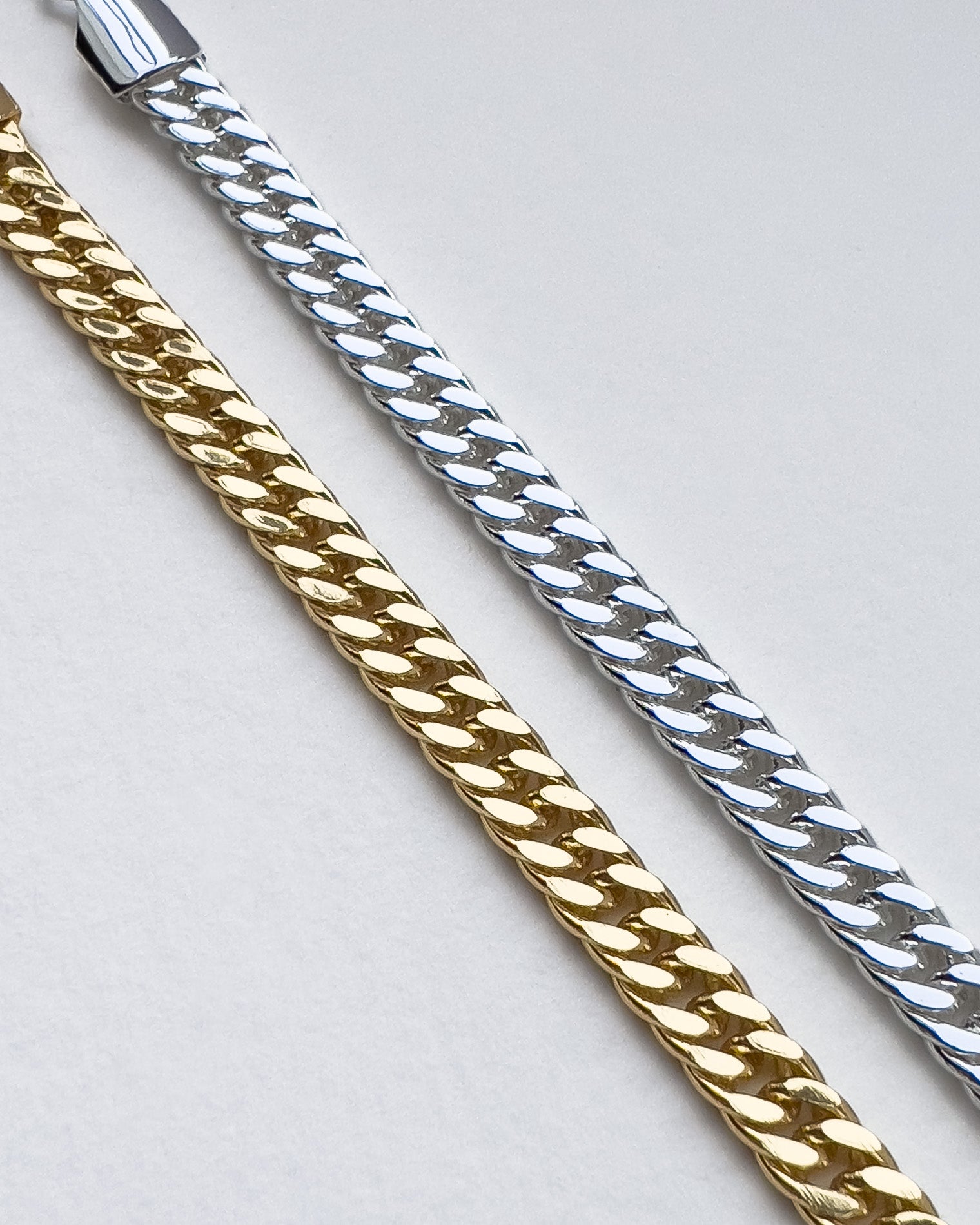 Two gold and silver chain necklaces on a light gray background